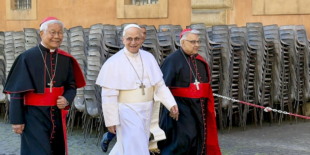 Papst Leo XIV. läuft mit zwei Kardinälen durch die Straßen des Vatikans.