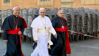 Papst Leo XIV. läuft mit zwei Kardinälen durch die Straßen des Vatikans.