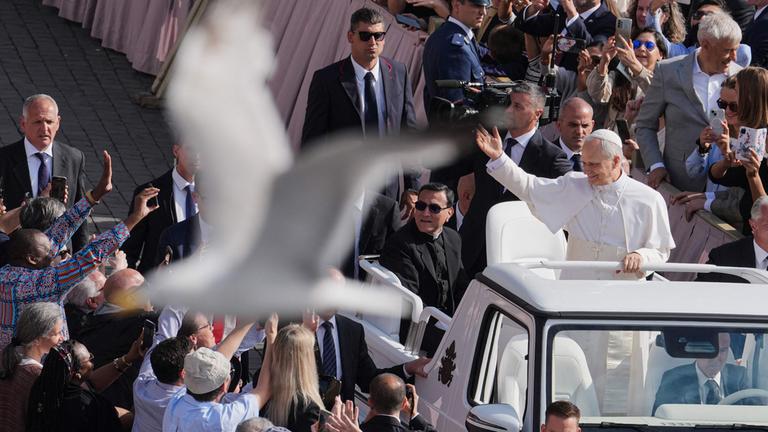 Ein Vogel fliegt ins Bild von Papst Leo XIV der die Besucher auf dem Petersplatz segnet. Aufgenommen am 18.05.2025