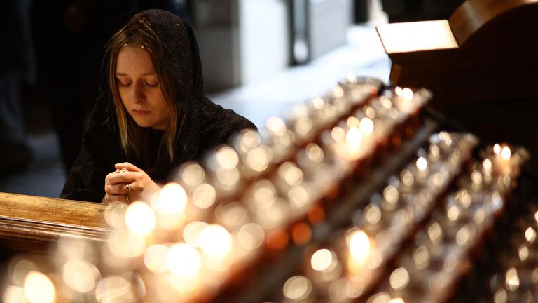Eine Frau betet kniend vor entzündeten Kerzen in der Westminster Cathedral