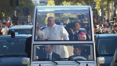 Papst Leo steht in Fahrzeug mit Glasdach auf Straße in Paris und winkt Menschen am Straßenrand zu