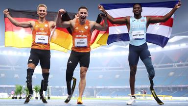 Johannes Floors und Felix Streng (Team Deutschland) sowie Sherman Guity Guity (Costa Rica) nach dem 100-Meter-Finale (T64) bei der Para-WM in Neu-Delhi am 30.09.2025.