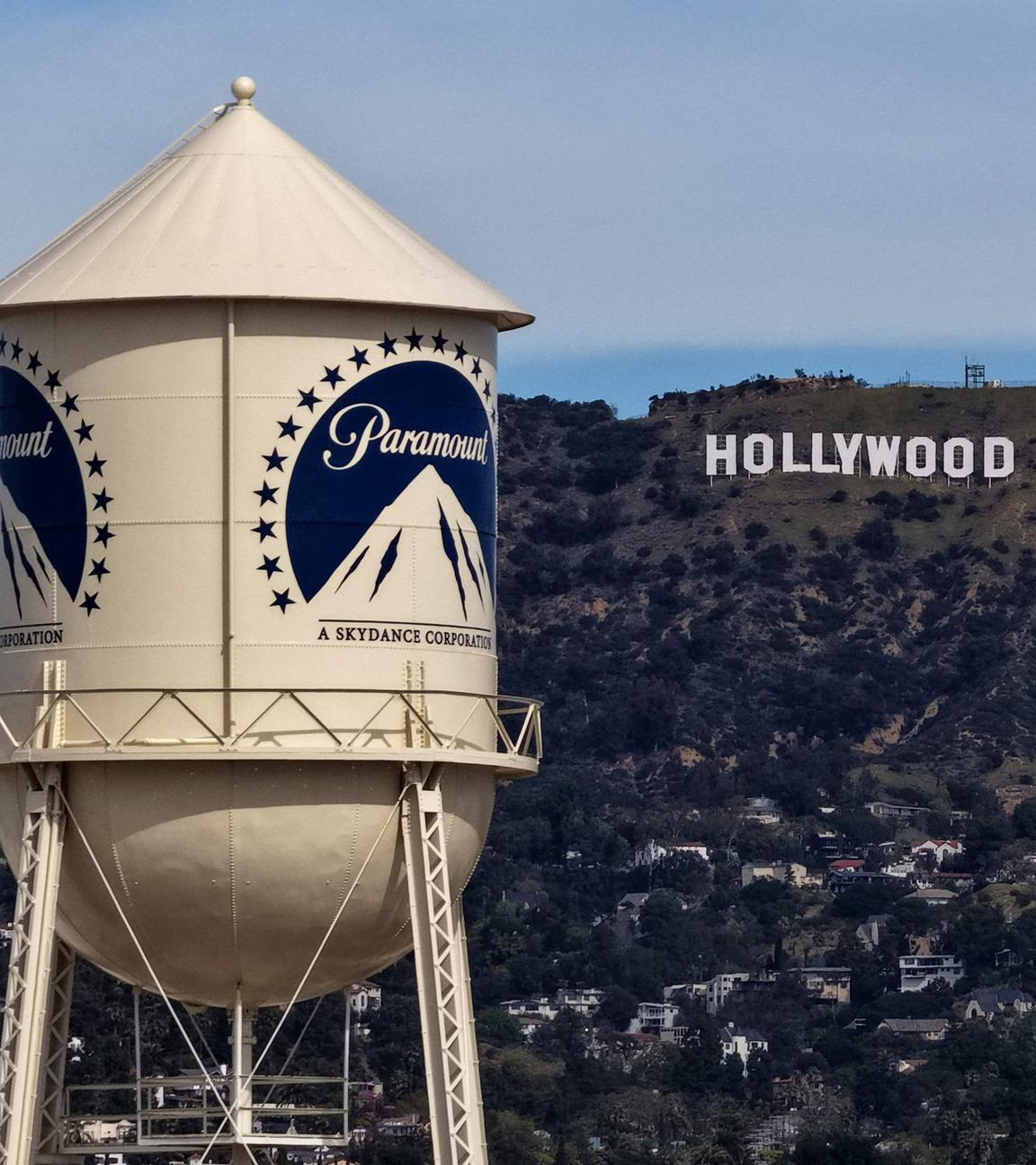 Ein Wasserturm mit Paramount Logo. Im Hintergrund sind die Hollywood Hills mit dem berühmten Schriftzug "Hollywood".