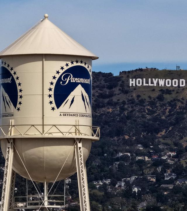 Ein Wasserturm mit Paramount Logo. Im Hintergrund sind die Hollywood Hills mit dem berühmten Schriftzug "Hollywood".