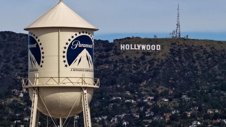 Ein Wasserturm mit Paramount Logo. Im Hintergrund sind die Hollywood Hills mit dem berühmten Schriftzug "Hollywood".