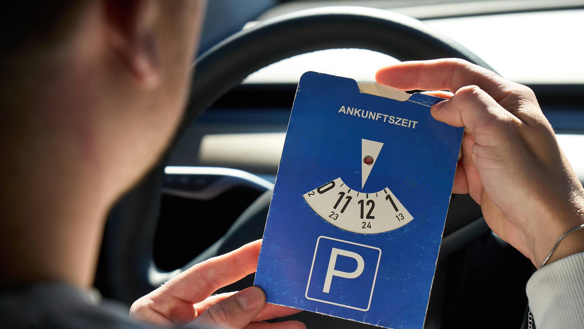 Mann stellt Parkscheibe im Auto.