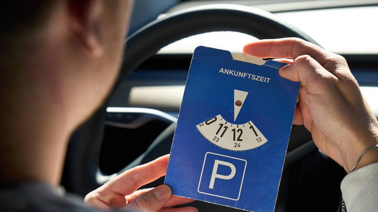 Mann stellt Parkscheibe im Auto.