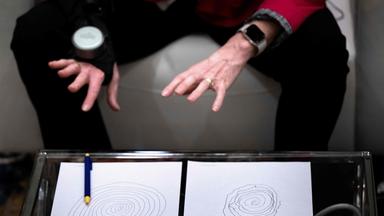 Älterer Mann mit Parkinson benutzt einen Handschuh, den GyroGlove, der zur Stabilisierung dient und das Zittern der Hände neutralisieren soll.