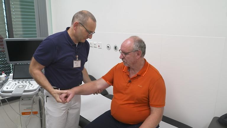 Arzt untersucht Arm eines Patienten