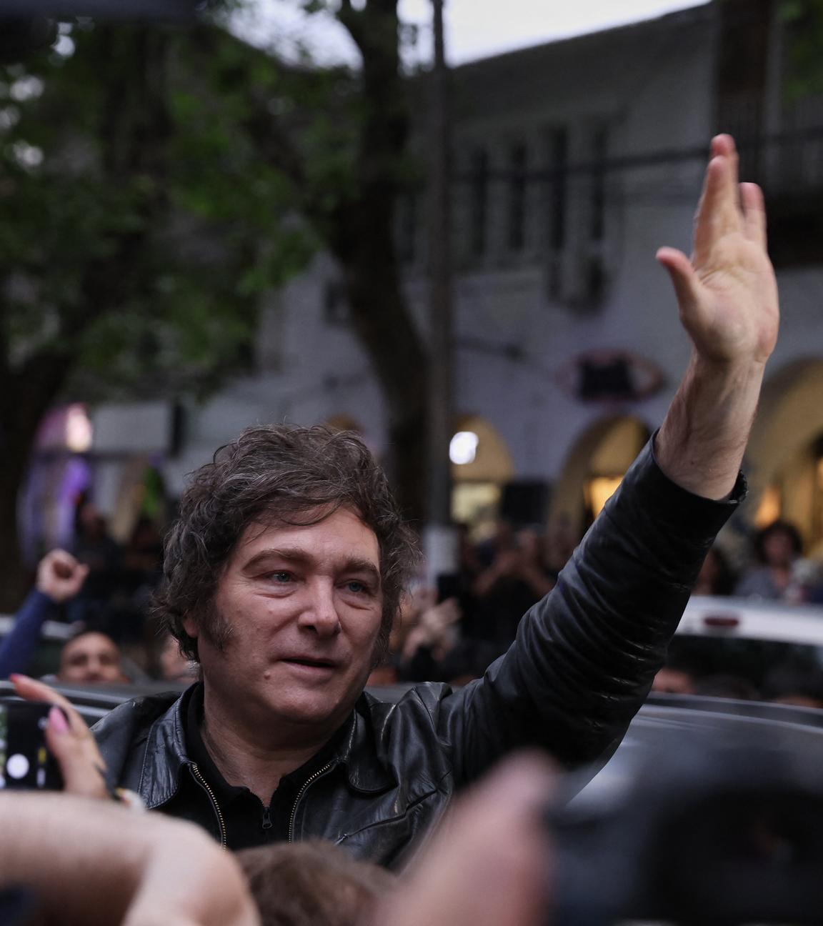 Javier Milei in einer Menschenmenge, hebt die Hand in die Luft.