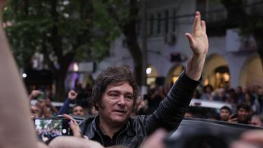 Javier Milei in einer Menschenmenge, hebt die Hand in die Luft.