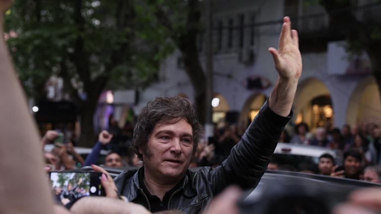 Javier Milei in einer Menschenmenge, hebt die Hand in die Luft.