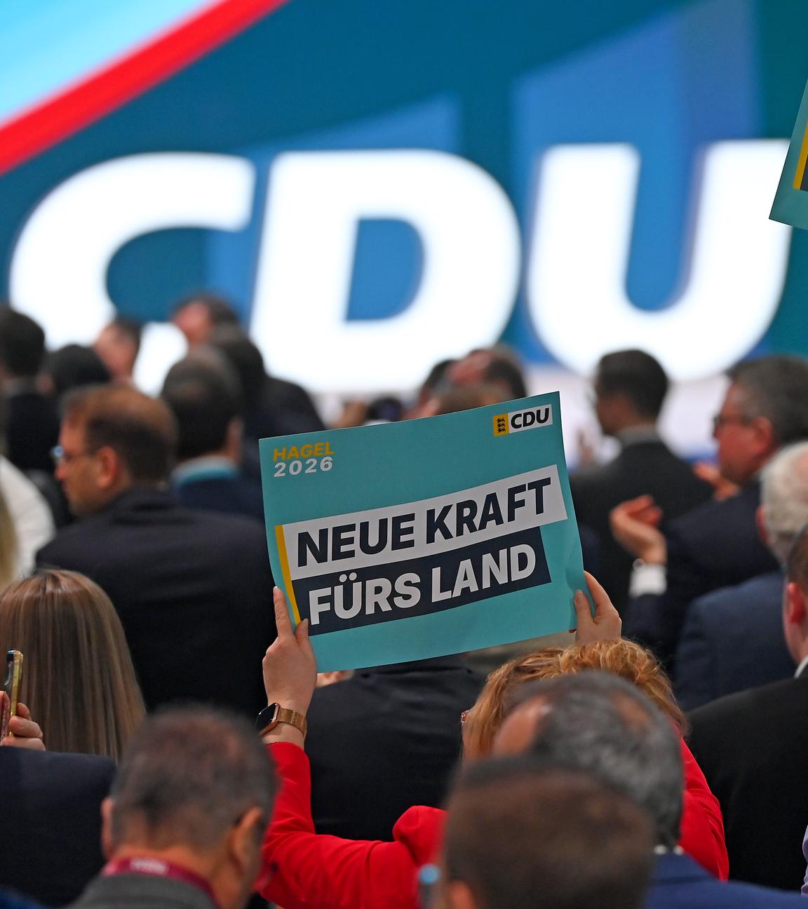 "Neue Kraft fürs Land" steht auf hochgehaltenen Schildern im Publikum vor einer Bühne mit CDU-Logo.