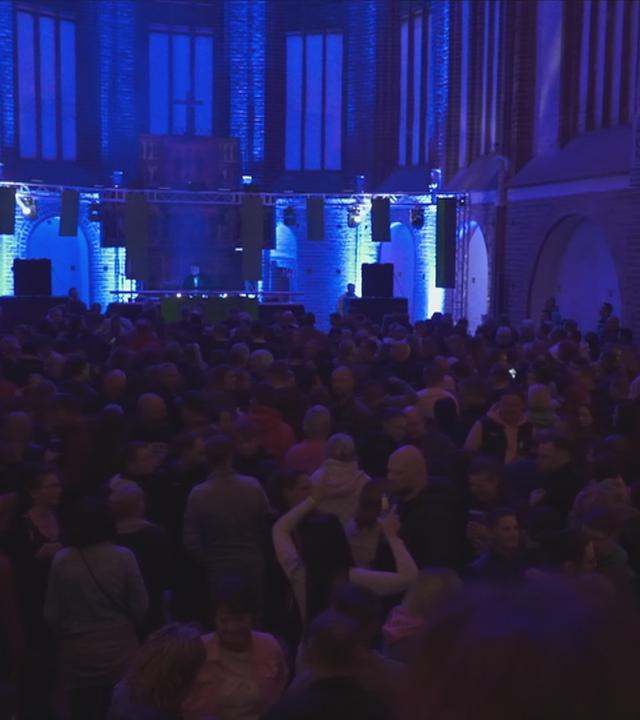 Viele Menschen in einer Kirche feiern bei Musik