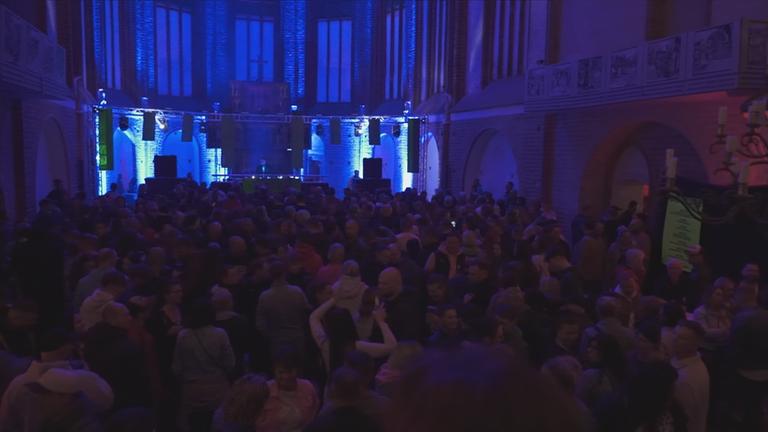 Viele Menschen in einer Kirche feiern bei Musik