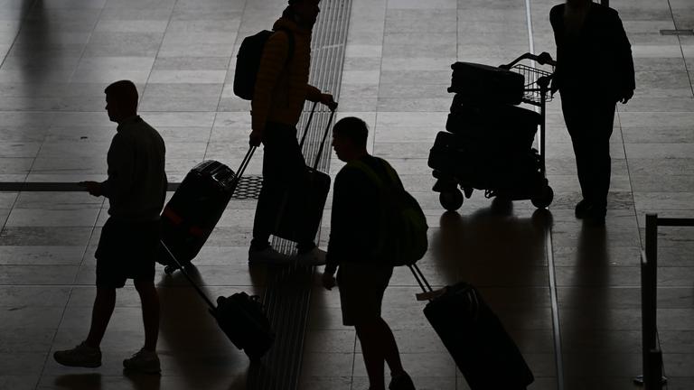 Reisende gehen am Flughafen BER durch das Terminal 1. 