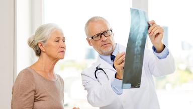 Ältere Patientin bespricht mit ihrem Arzt eine Röntgenaufnahme