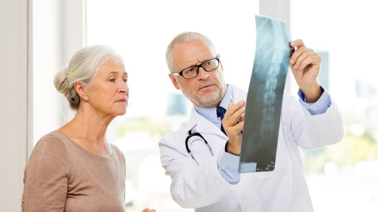 Ältere Patientin bespricht mit ihrem Arzt eine Röntgenaufnahme