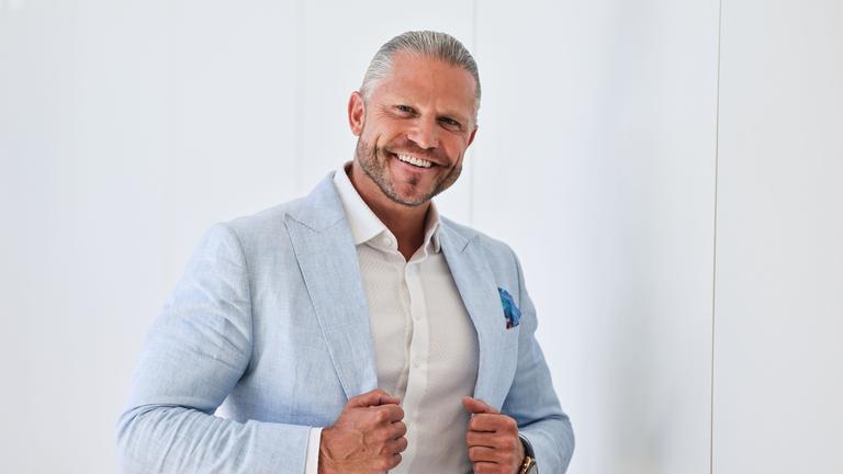 Paul Janke lacht in einem hellblauen Jacket in die Kamera.
