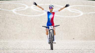 Pauline Ferrand-Prevot fährt als Mountainbike-Olympiasiegerin jubelnd mit ausgespreitzen Armen durchs Ziel.