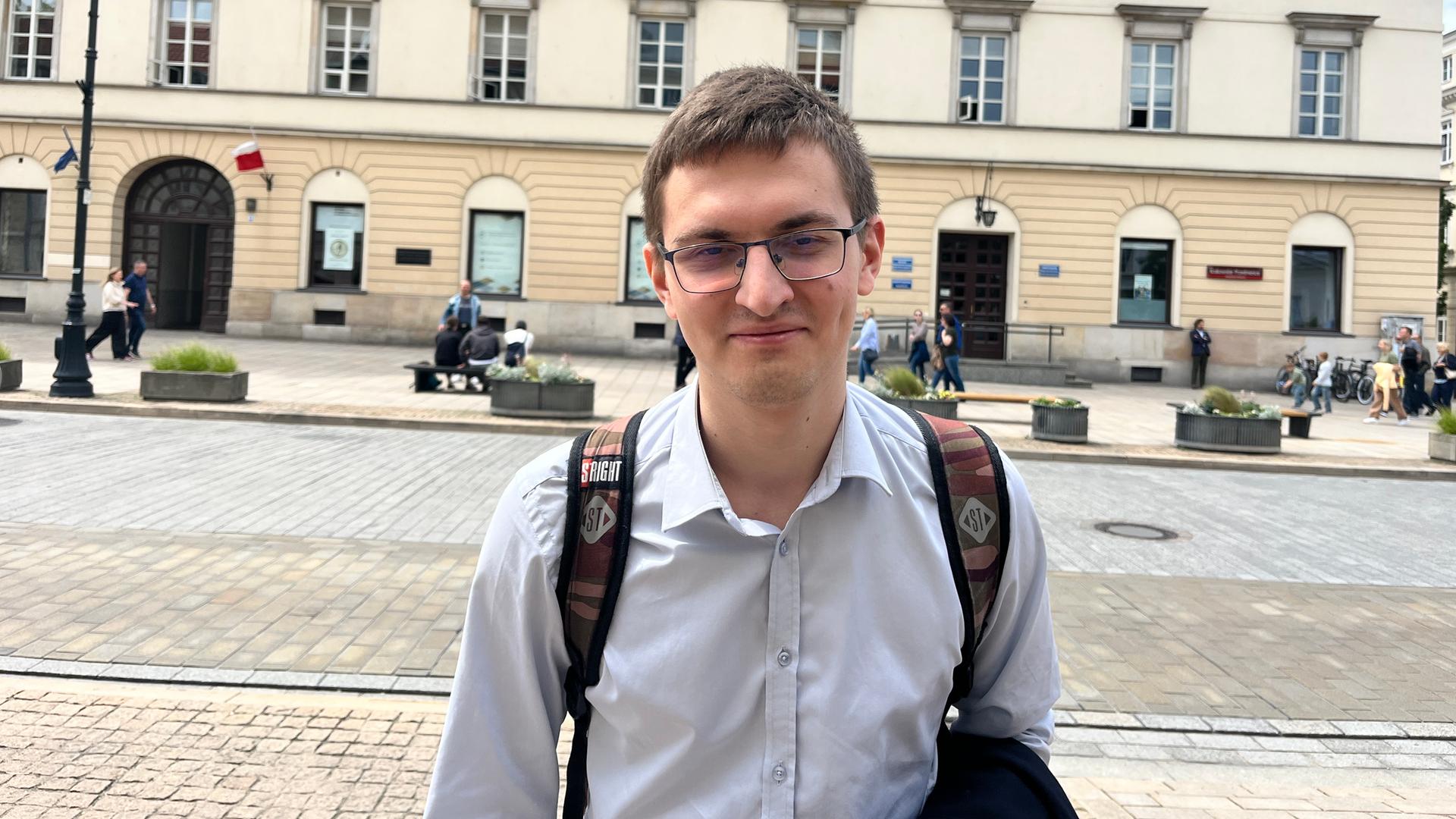 Paweł Cilke steht an einer breiten Straße in Warschau