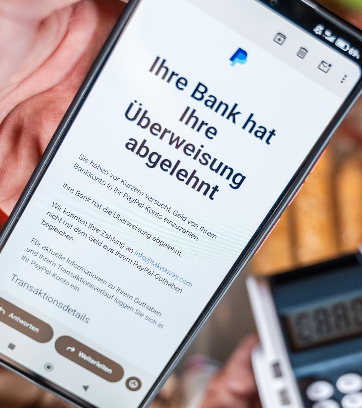 Ein Smartphone zeigt eine Paypal-Mitteilung über eine abgelehnte Überweisung per E-Mail. 