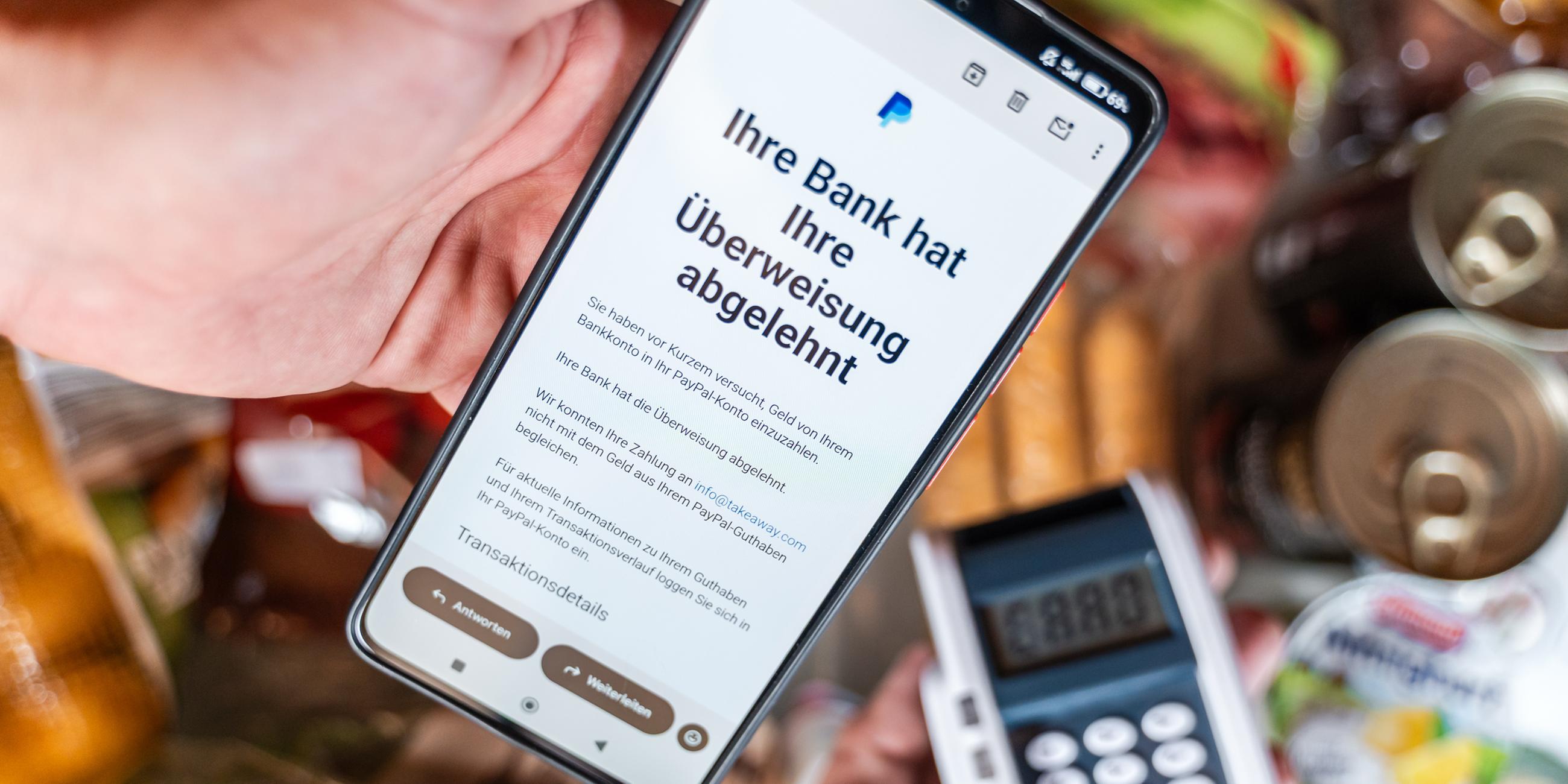 Ein Smartphone zeigt eine Paypal-Mitteilung über eine abgelehnte Überweisung per E-Mail. 
