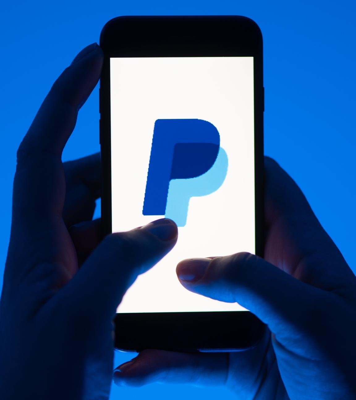 12.05.2022, Sachsen, Dresden: Eine Frau hält ein Smartphone mit dem Logo des Bezahldienst Paypal. (gestellte Szene)