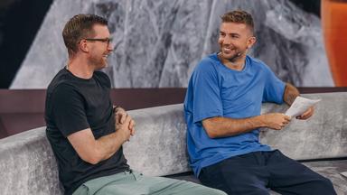 Per Mertesacker und Christoph Kramer lachen sich auf dem Sofa im WM-Studio an. 