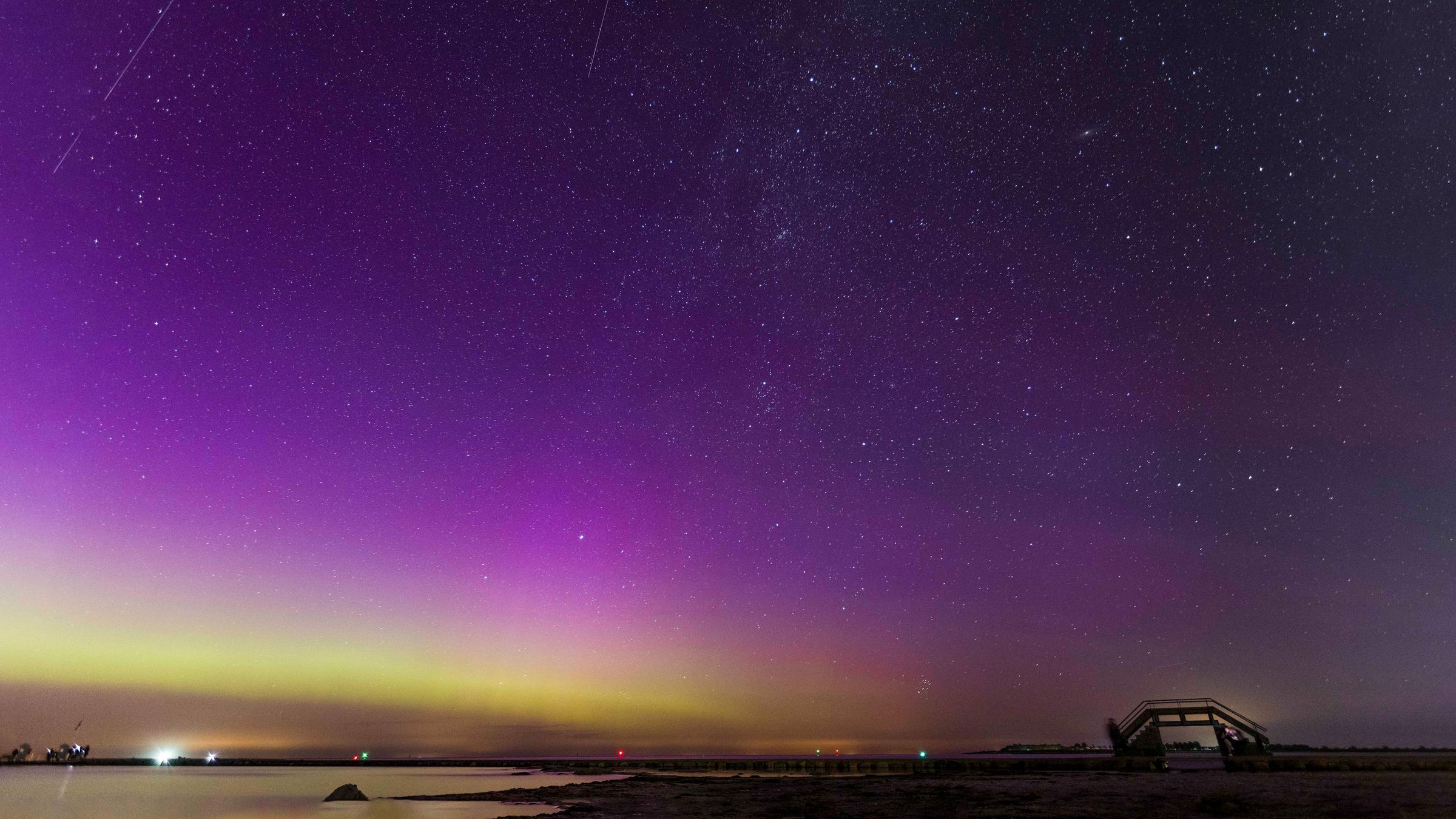 Polarlichter und eine Sternschnuppe der Perseiden sind bei sternenklarer Nacht über der Ostsee zu sehen