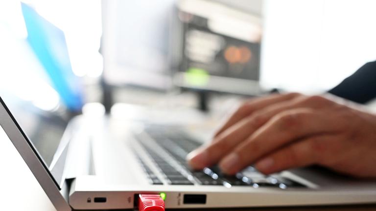 Symbolbild: Ein Mitarbeiter sitzt an einem Arbeitsplatz vor einem Laptop (gestellte Szene).