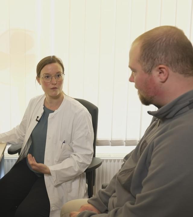 Ärztin sitzt mit Depressions-Patient an Schreibtisch vor PC mit MRT-Bild