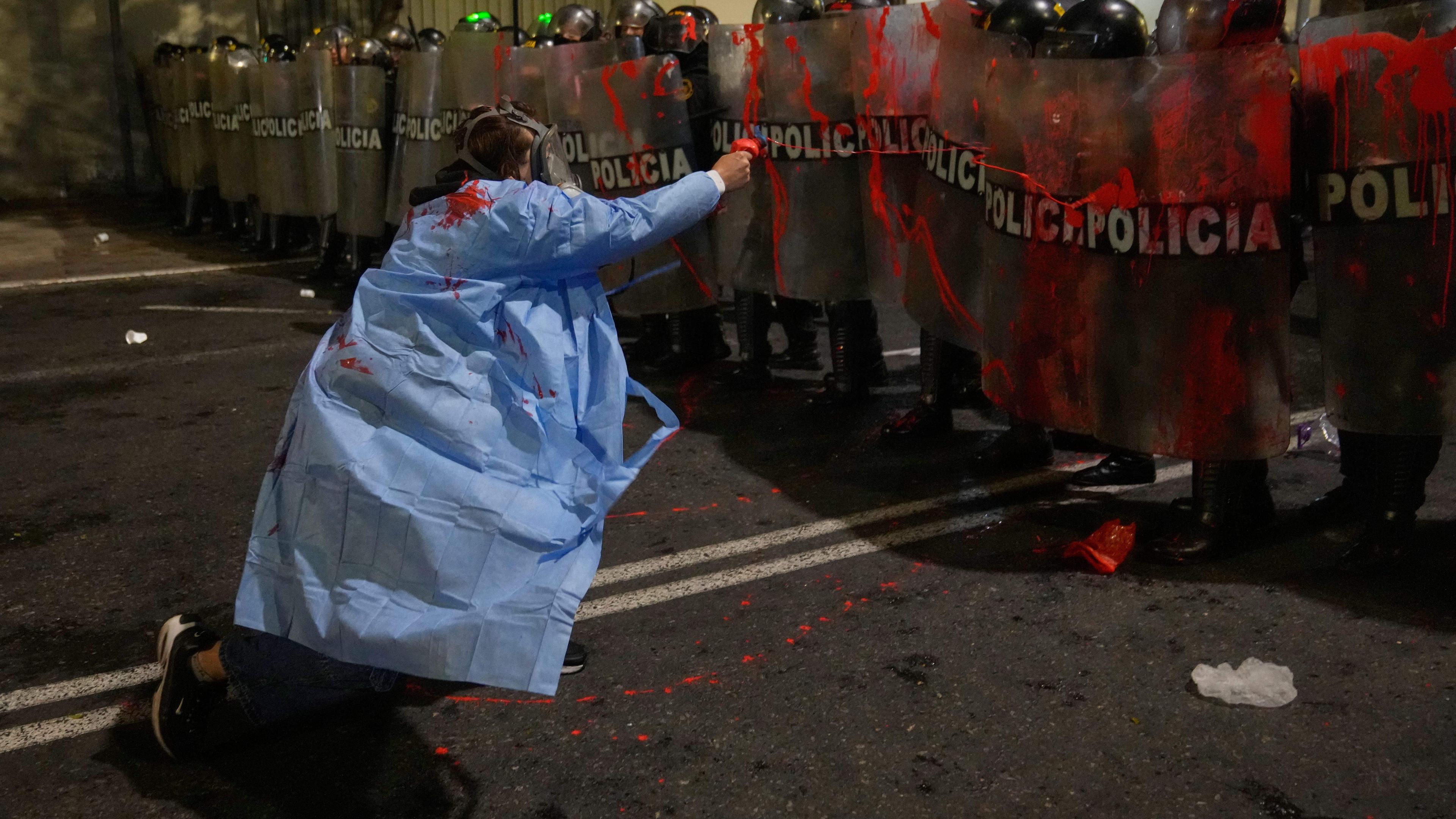 Ein Demonstrant besprüht Bereitschaftspolizisten mit roter Farbe.