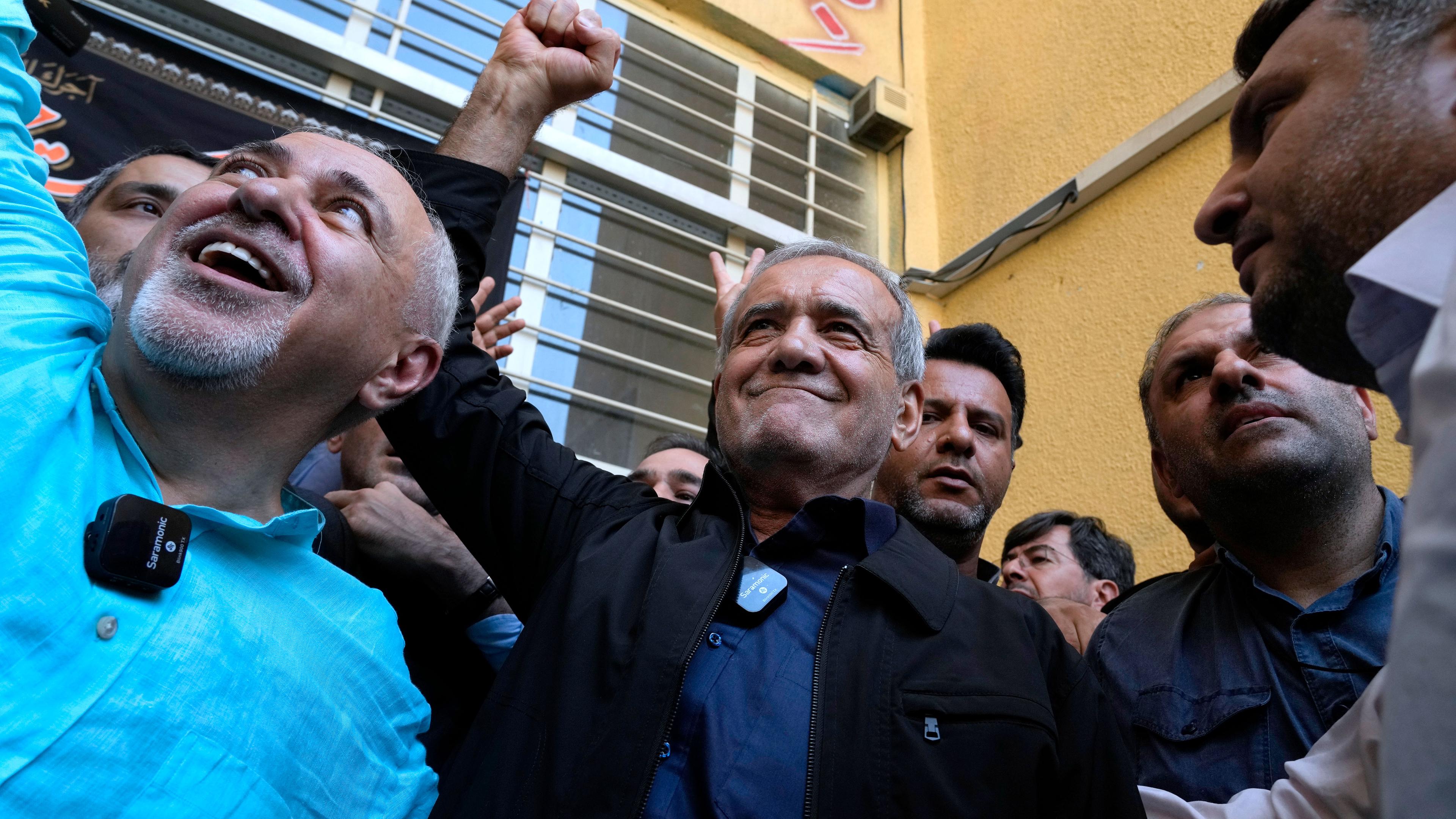 Iran, Teheran: Reformkandidat für die iranischen Präsidentschaftswahlen, Massud Peseschkian (M), ballt seine Faust, nachdem er seine Stimme in einem Wahllokal in Shahr-e-Qods bei Teheran abgegeben hat.
