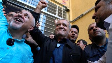 Iran, Teheran: Reformkandidat für die iranischen Präsidentschaftswahlen, Massud Peseschkian (M), ballt seine Faust, nachdem er seine Stimme in einem Wahllokal in Shahr-e-Qods bei Teheran abgegeben hat.