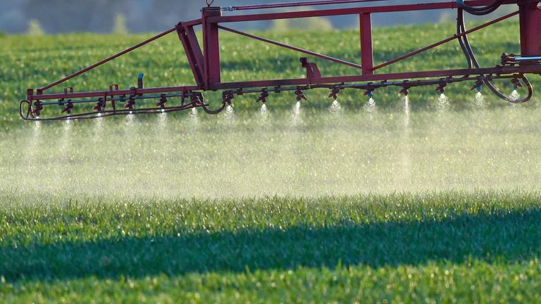 Ein Landwirt fährt mit einem Traktor und sprüht Pestizide.