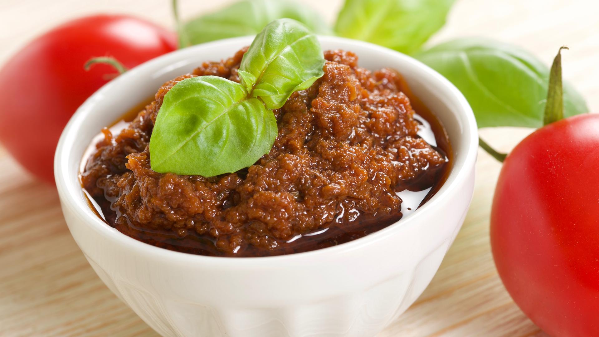 Pesto rosso mit Basilikumblatt garniert