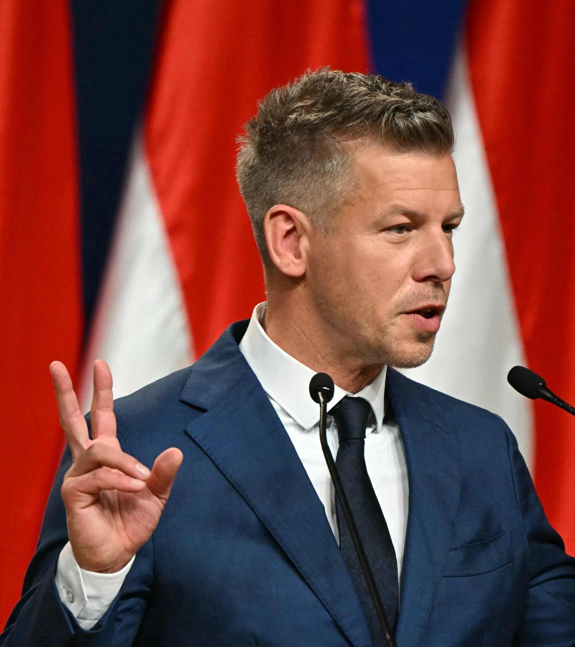 Peter Magyar bei einer Pressekonferenz, gestikuliert und hält beide Hände ähnlich des Victory-Zeichens neben sich hoch.