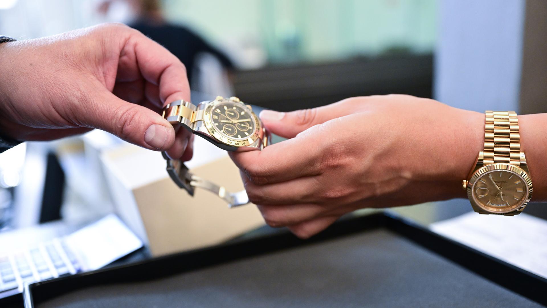 Eine Luxusuhr wird in einem Pfandleihhaus von einer Hand in die andere gegeben.
