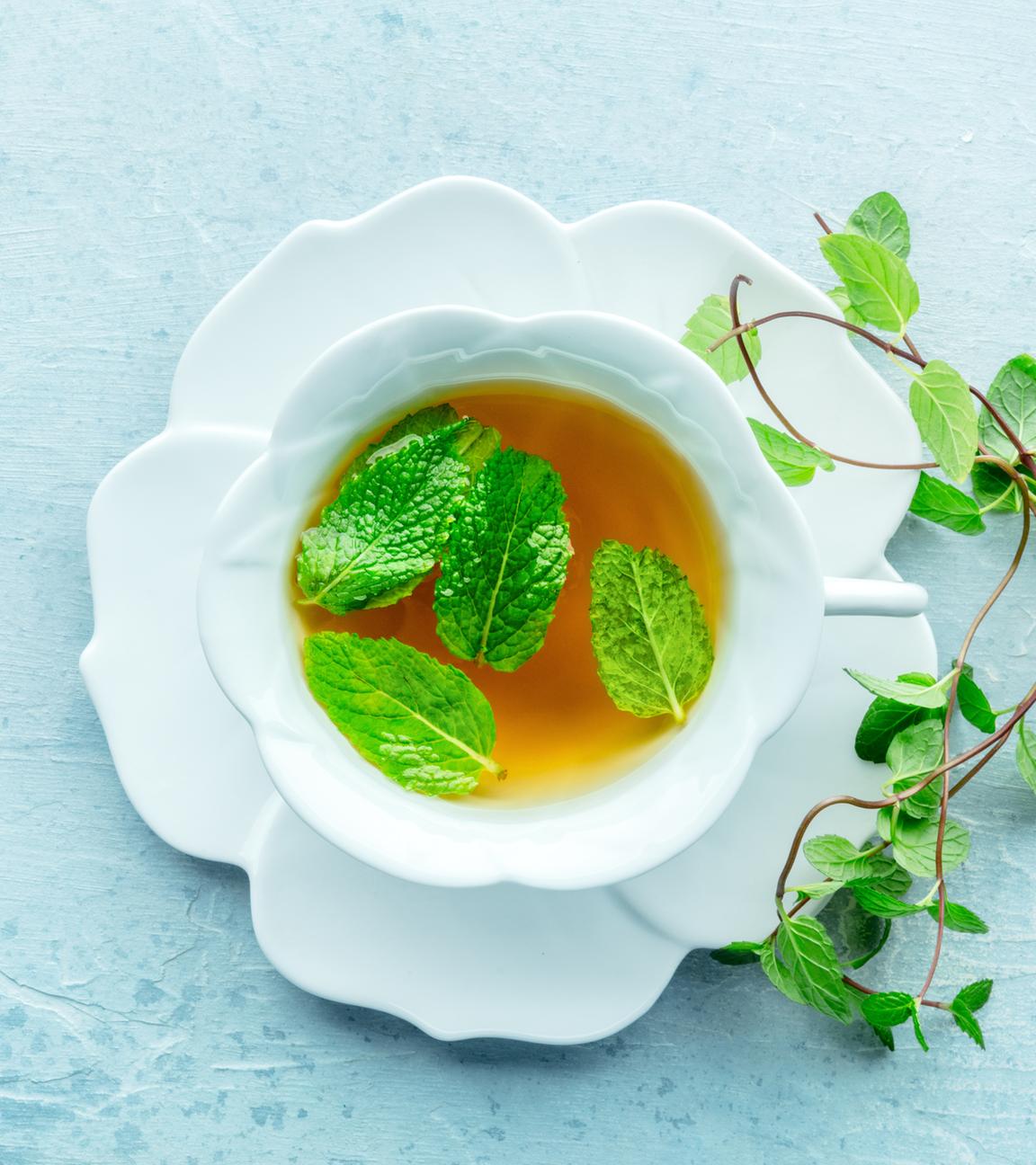Eine Tasse Pfefferminztee mit frischen Minzblättern, über Kopf
