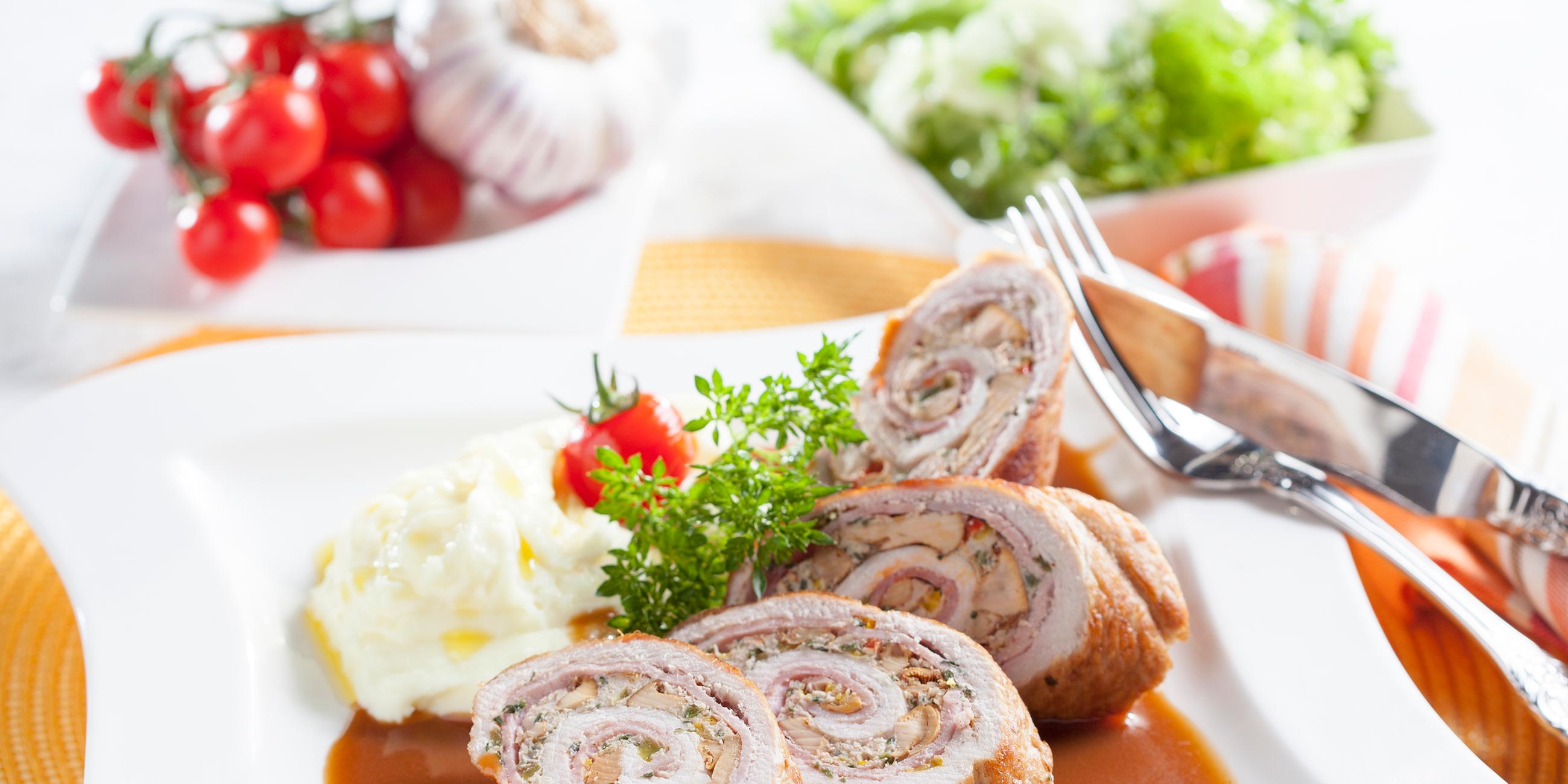 Scheiben von der Pfifferling-Schinkenroulade mit Sellerie-Kartoffelpüree auf einem Teller angerichtet.