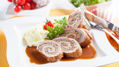 Scheiben von der Pfifferling-Schinkenroulade mit Sellerie-Kartoffelpüree auf einem Teller angerichtet.