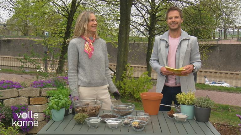 Anja Koenzen und Florian Weiss stehen vor einem Tisch mit Blumentöpfen und Erde