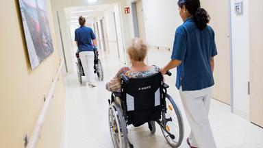 Archiv: Zwei Pflegerinnen schieben in einem Klinikum Patienten mit Rollstühlen durch einen Flur