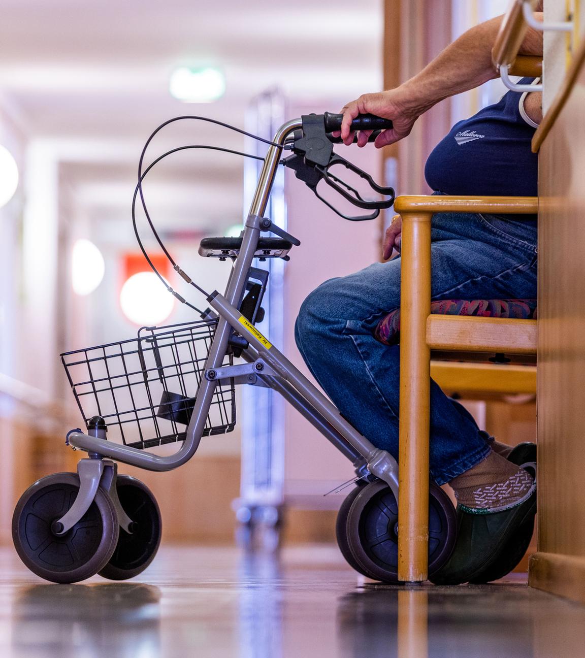 Symbolbild:  Ein Bewohner sitzt mit seinem Rollator auf einem Flur in einem Pflegeheim.