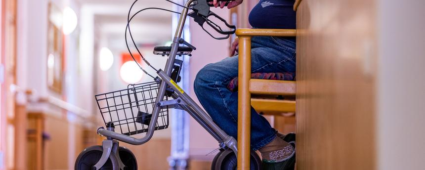 Symbolbild:  Ein Bewohner sitzt mit seinem Rollator auf einem Flur in einem Pflegeheim.
