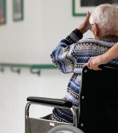 Pflegerin schiebt eine alte Frau im Rollstuhl