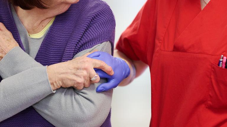 Eine Pflegekraft nimmt im DRK-Pflegezentrum Solferino eine Bewohnerin an der Hand. 