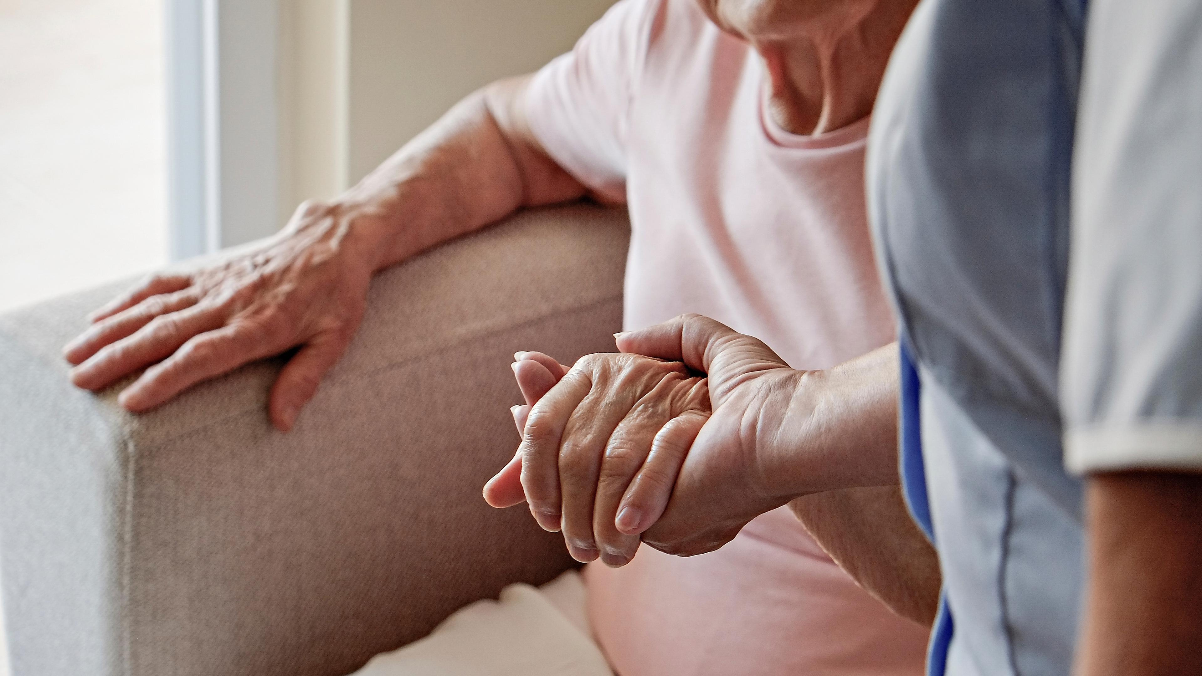 Frau hält Hand einer älteren Dame