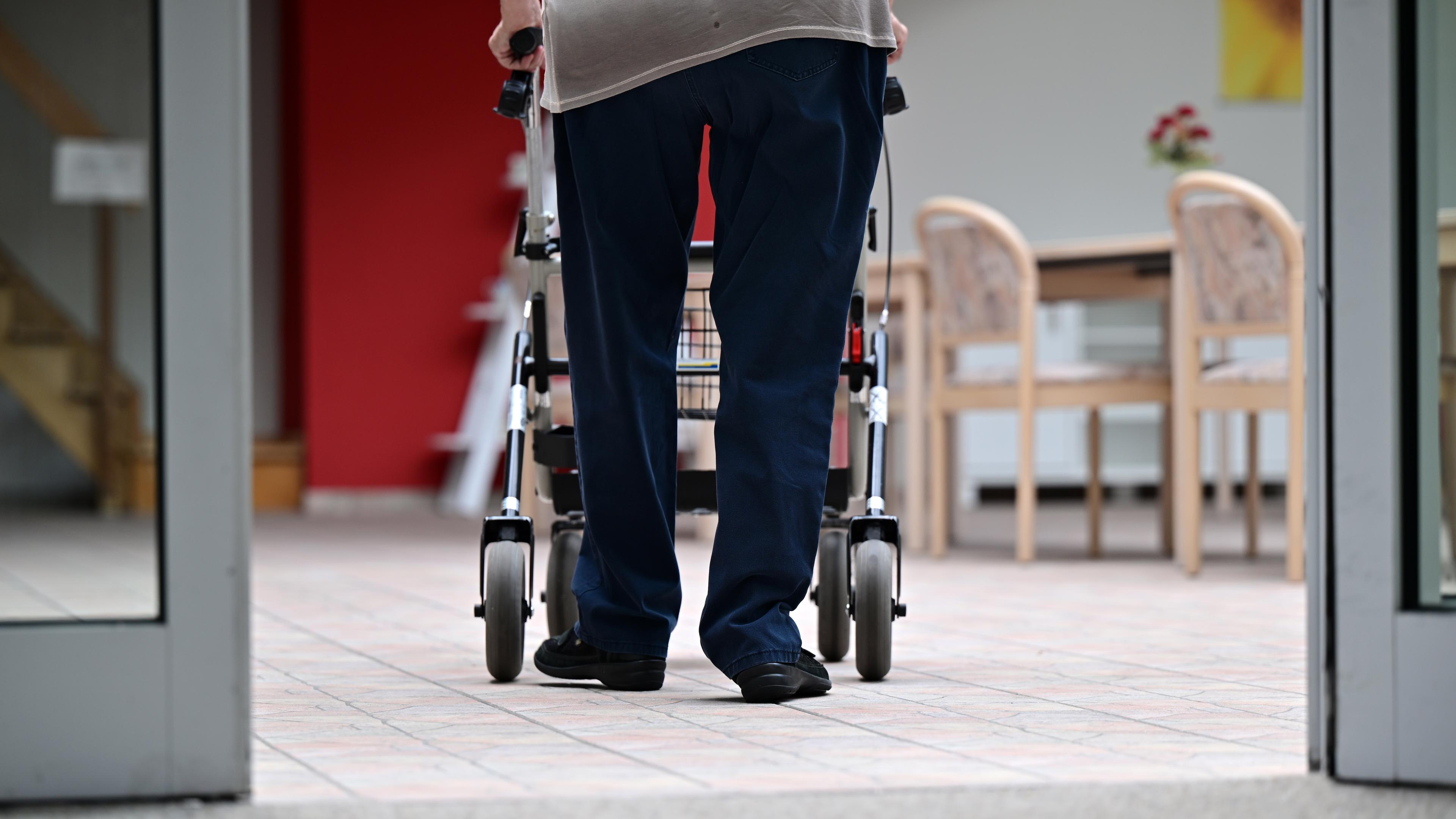 Ein Bewohner eines Pflegezentrums geht mit dem Rollator durchs Haus.